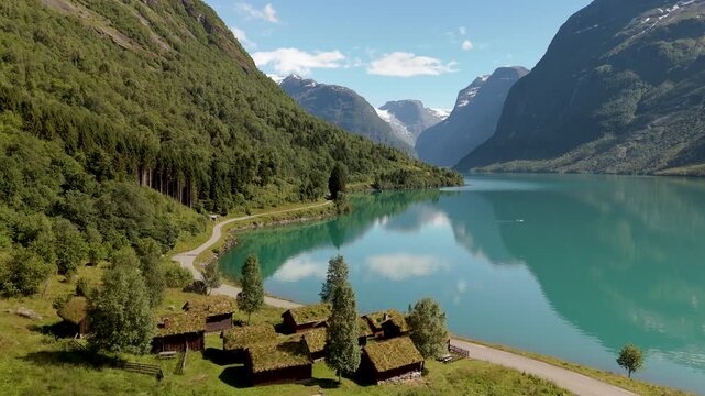 An aerial view of G Lovatnet Lake Lodal valley in Norway features its tranquil blue waters, lush mountains, and rustic cabins perfect serene destination for travelers seeking nature beauty