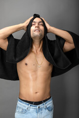 Cropped view of a young shirtless athlete with black towel after shower, bath or sauna. Indian bodybuilder with happy, mischievous facial expressions posing for camera