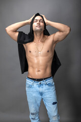 Naklejka premium Cropped view of a young shirtless athlete with black towel after shower, bath or sauna. Indian bodybuilder with happy, mischievous facial expressions posing for camera