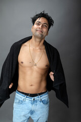 Naklejka premium Cropped view of a young shirtless athlete with black towel after shower, bath or sauna. Indian bodybuilder with happy, mischievous facial expressions posing for camera