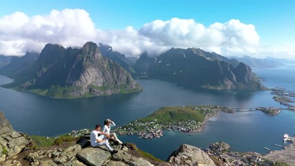 panoramic view from Reinebringen in Lofoten, Norway, reveals majestic mountains and serene waters, ma couple of man and woman hiking Reinebringen adventure and travel enthusiasts alike