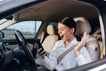 Woman, car, driver's seat, cell phone, surprised a surprised woman is sitting in the driver's seat of a car, holding a cell phone with her mouth open