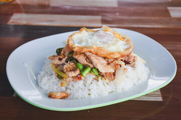 Pork with basil and fried egg on rice is ready to eat on the table.