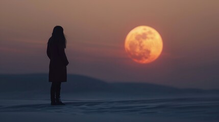 Obraz premium Woman Stands on Beach Watching Sunset Over Ocean Horizon