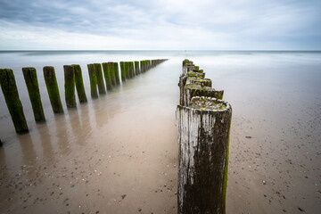 Linie von Holzpfählen im Meer bis zum Horizont