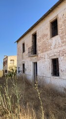 Casa abandonada y destrozada en medio del campo. Plantas silvestres y día soleado de verano....
