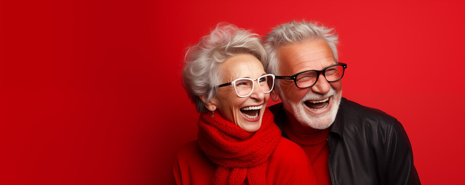 Crazy smiling senior couple, isolated red color background, image with space for text