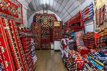 Turkish antique carpet sales shop.Pile of beautiful handmade carpets on the traditional Middle East market bazaar. Turkish colourful carpets.