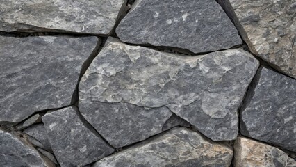 Obraz premium Close-up of a dry stone wall with irregularly shaped gray stones tightly stacked together. The image showcases the rough texture and natural patterns of the stones, ideal for backgrounds
