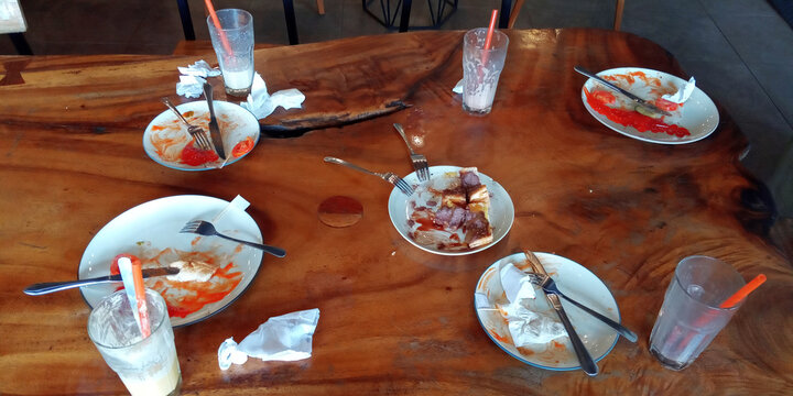The leftover food and dirty empty dishes on the restaurant table.