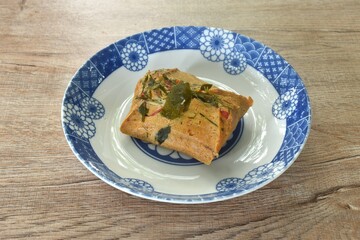 steamed chop clown knifefish with curry dressing coconut milk and topping slice lemon grass leaf on plate 