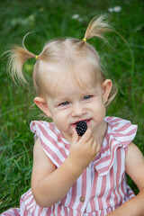 little girl eats blackberry on the background of nature. Selective focus