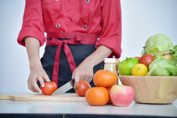 Close up Females Chef hands holding chop Wooden cutting board home kitchen. Women Chef hand cutting slice red tomato prepare fruit vegetables. Crop Woman hands use knife chopping organic tomato