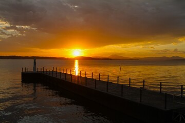 Obraz premium a lighthouse with colorful sky and reflection on lake during sunset with far view of mountains