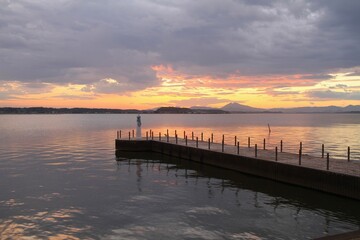 Obraz premium a lighthouse with colorful sky and reflection on lake during sunset with far view of mountains