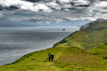 Couple With Dog Walks Along The Atlantic Coast On The Isle Of Skye In Scotland, UK