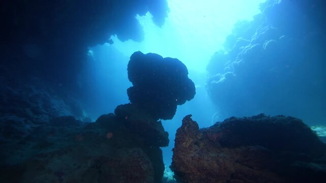 Coral cave caver with light rays penetrating the water