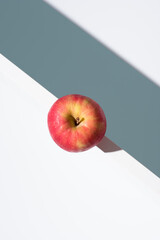 Una manzana roja sobre un soporte blanco y fondo verde. Vista superior	