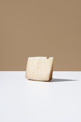 Trozo de queso de oveja curado. Cuña de queso manchego sobre fondo marrón