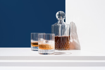 Un vaso de whisky escocés con hielo y decantador sobre fondo azul	