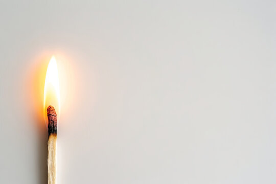 Close-up of a burning matchstick with a flame against a clean white background. Concept of fire, ignition, light, and heat. Copy space
