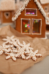 Cookies in the shape of snowflakes and a gingerbread house are on the festive table