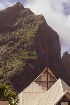 A cross on top of St Pierre church in vaitape, Bora Bora. The symbol of faith and Christianity in front of Mount Otemanu. 