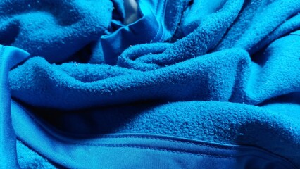 Soft Bright Blue Fleece Fabric Texture Background Featuring Folded Material Details and Cozy Warm Textile Surface Pattern © a little boys 