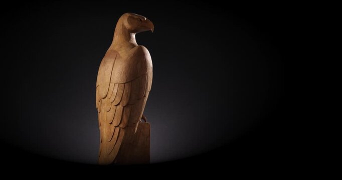 Rotation einer alten Holzskultpur eines Adlers Raubtier Greifvogels vor schwarzem Hintergrund