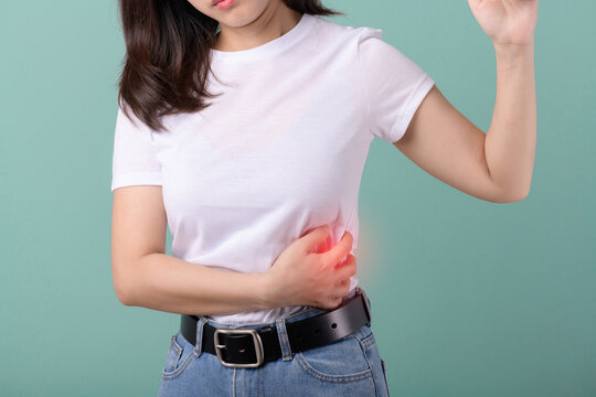 Salpingitis or stomached. Asian woman suffers lateral abdominal pain due to salpingitis isolated on green background. health concept.