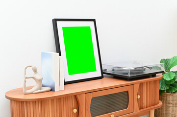 Stylish wooden cabinet with books, art pieces, and plants, and a green screen frame.