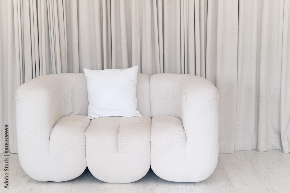 Poster a modern, plush sofa with a decorative pillow featuring abstract line art, exuding a cozy and inviti