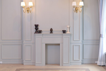 A minimalist and elegant interior featuring a light gray fireplace with decorative items on the mantel. The room exudes a calm and sophisticated atmosphere.