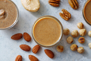 Homemade nuts butter in a glass jars with various nuts.