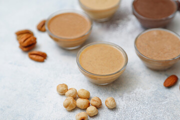 Homemade nuts butter in a glass jars with various nuts.