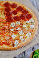 Hot tasty traditional various italian pizzas with salami, meat, cheese, onion, mushroom, tomatoes greens on a dark background