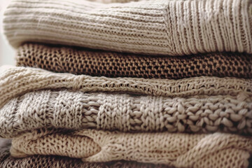 Stack of knitted sweaters, beige tones	