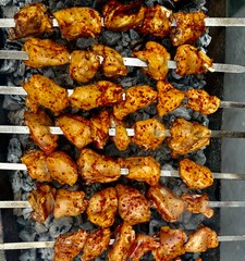 Marinated chicken skewers being grilled over charcoal outdoors