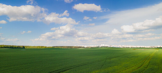 Landscape view from drone, green fields and haystacks, sky with white clouds. 
