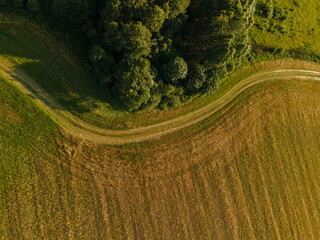 Landscape view from drone, yellow and green fields and haystacks, sky with white clouds. 