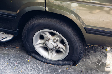 Fototapeta premium Destroyed blown out tire with exploded, shredded and damaged tire on a modern automobile.