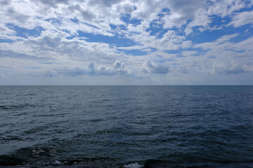 blue sky and white clouds over the calm sea surface. Beautiful seascape.