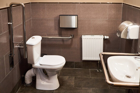 Interior of specially adapted bathroom toilet with friendly design for people with disability handicapped with disabilities or invalids in wheelchair with handrail handle toilet.