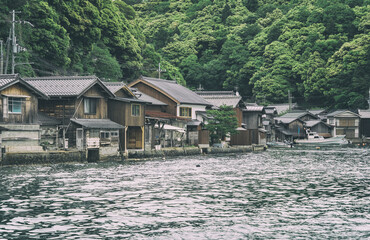 Naklejka premium Beautiful scenic view with the wooden traditional waterfront boat houses called funaya around Ine Bay, in the village Ine, Japan