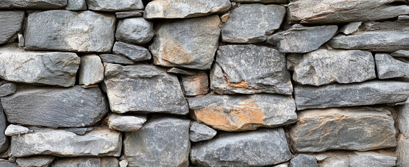 Photo of a stone wall texture background, seamless pattern of grey rocks. 