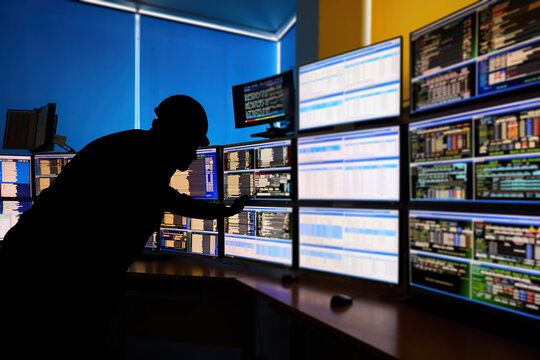 SCADA system in the central heating process.  Silhouette of an operator analyzing data on multiple monitors - ensuring optimal performance and safety in industrial automation systems.