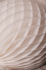 A close-up shot of a white, honeycomb paper decoration, showcasing intricate textures and soft lighting.