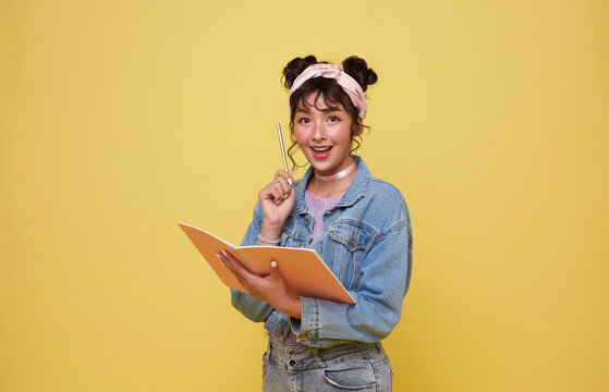 back to school. happy smiling young Asian college student with notebook think something ready to school isolated on yellow background.