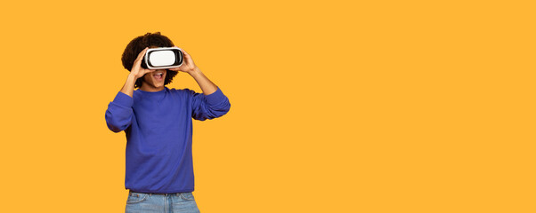 A young boy wearing a blue sweater is engaged in an exciting experience with a virtual reality headset. He is joyful and enthusiastic as he interacts with a digital world, copy space