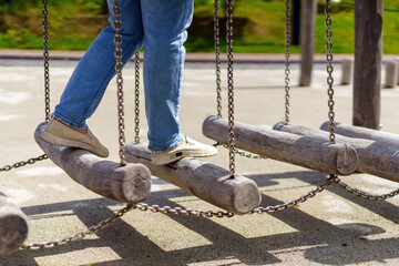 person navigates a challenging fitness apparatus: swinging logs suspended by metal chains,...